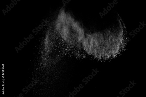 Freeze motion of white particles on black background. Powder explosion. Abstract dust overlay texture.