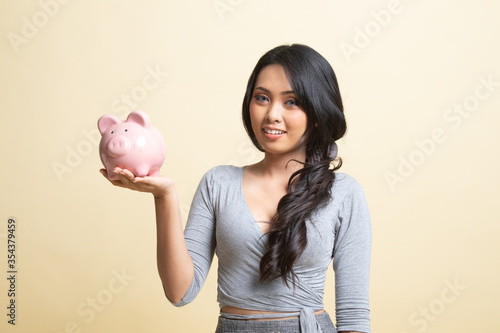 Young Asian woman with a pig coin bank.