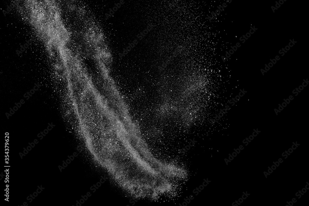 Obraz premium Freeze motion of white particles on black background. Powder explosion. Abstract dust overlay texture.