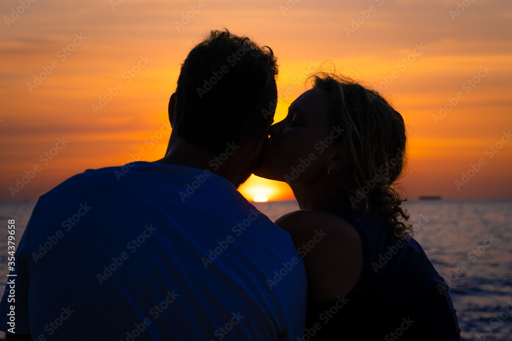 Kissing couple at sunset on the beach.