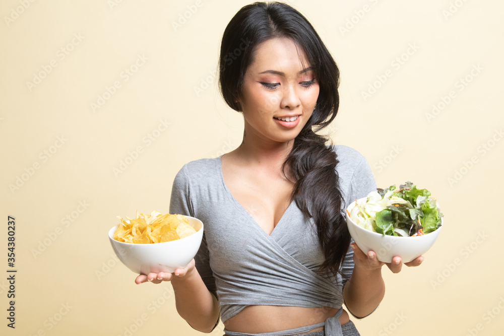Young Asian woman with potato chips and salad. Young Asian woman with potato chips and salad.