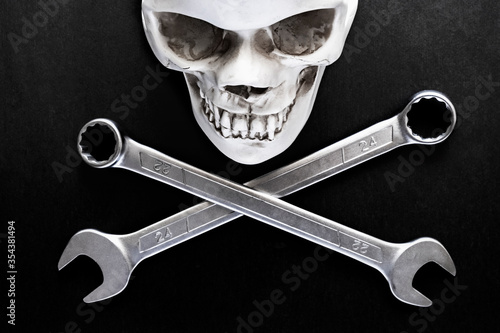 Two crossed wrenches or spanners and skull on black backgorund for concept design. Repair service. Service concept. Pirate sign, motorcycle repair, bikers concept.