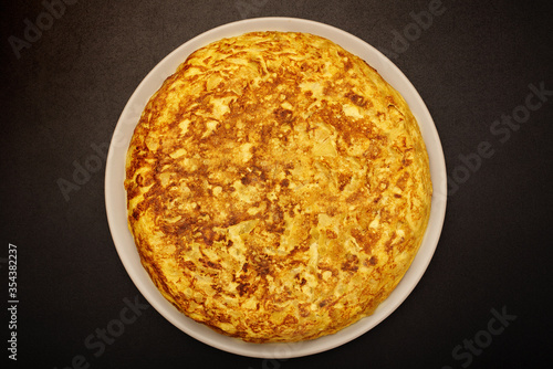 Spanish omelette on a black background. Cooked with eggs, potatoes and onions. Typical spanish food.