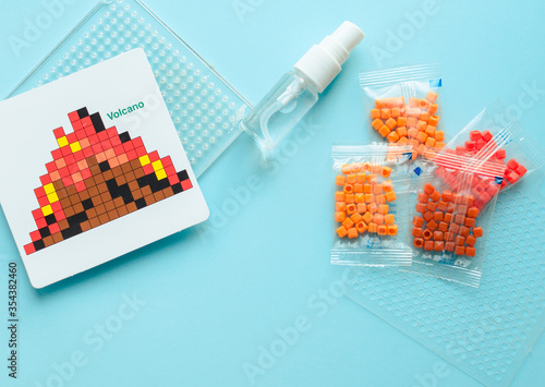 make beads figures on the table. Step-by-step instruction. Close-up. Handcraft with child's hands, handmade aqua mosaic on the table during the assembly process, selective focus.  dinosaur mosaic