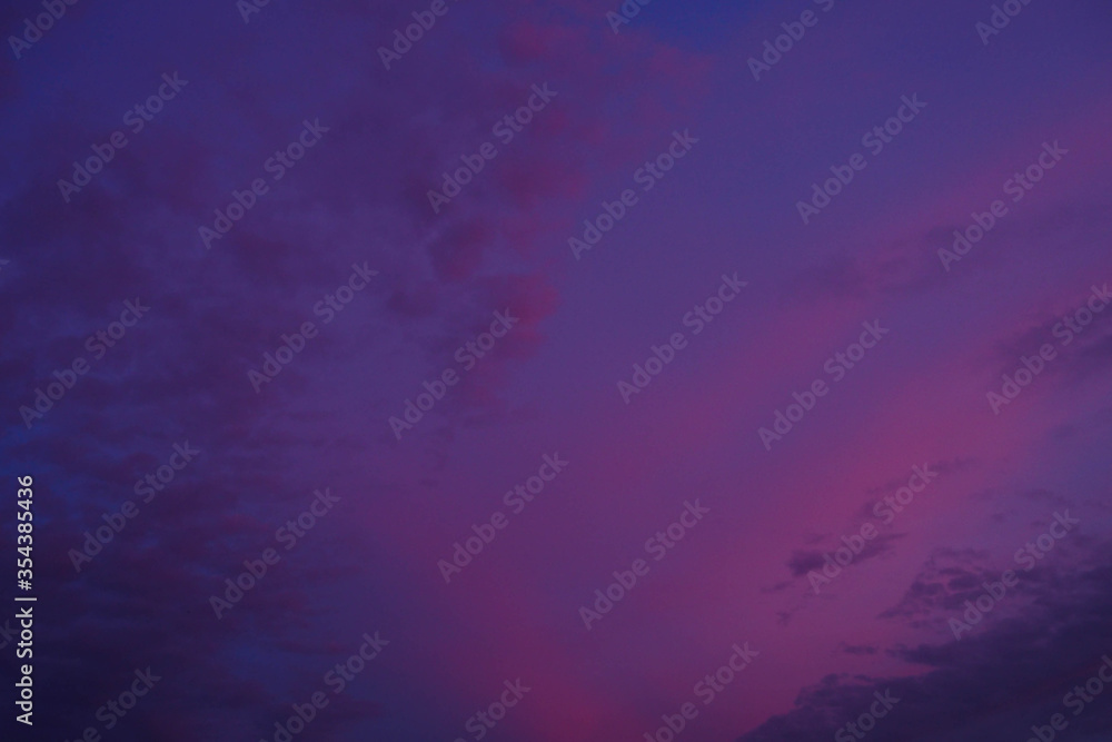 sunset with pink and purple flowers in the sky with clouds . the color of the sky