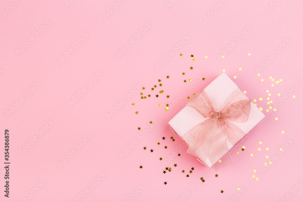 Gift or gift box and stars confetti on a pink table from above. Flat composition for birthday Gift or gift box and stars confetti on a pink table from above. Flat composition for birthday
