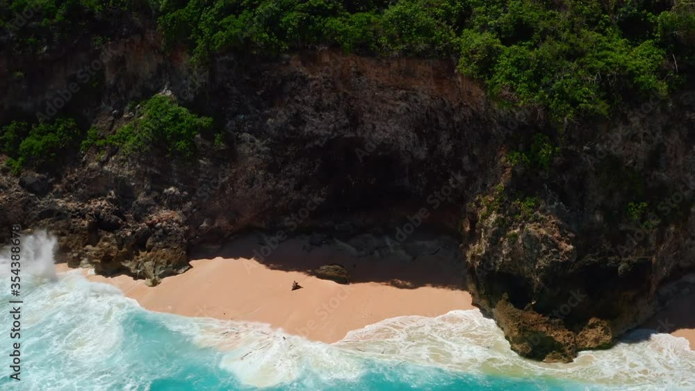 Aerial top view of ocean blue waves break on a beach. Sea waves and beautiful sand beach aerial view drone shot. Bird's eye view of ocean waves crashing against an empty sand beach from above. Aerial top view of ocean blue waves break on a beach. Sea waves and beautiful sand beach aerial view drone shot. Bird's eye view of ocean waves crashing against an empty sand beach from above.