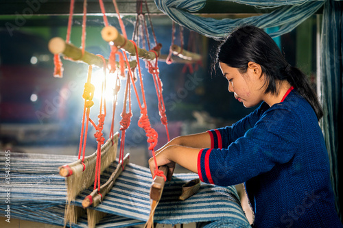 Crafts and craftsmanship. Traditional Isan Thai Cotton indigo weaving. Young woman weaving Cotton Indigo in traditional way at manual loom. Thailand . Selective focus.