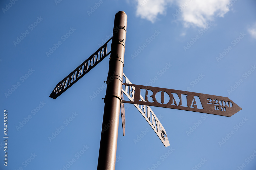 Fototapeta premium Street sign in retro style indicating directions to different places of the world: Rome, Berlin, Moscow and the information of distance in kilometers.