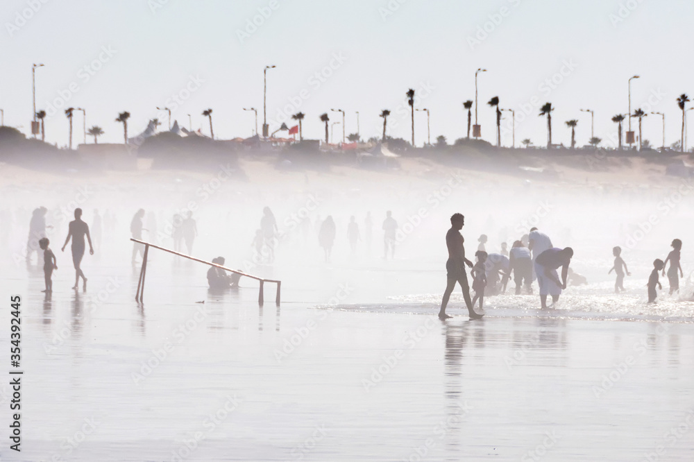 Silhouettes of various people playing football, walking and running at the beach in Morocco