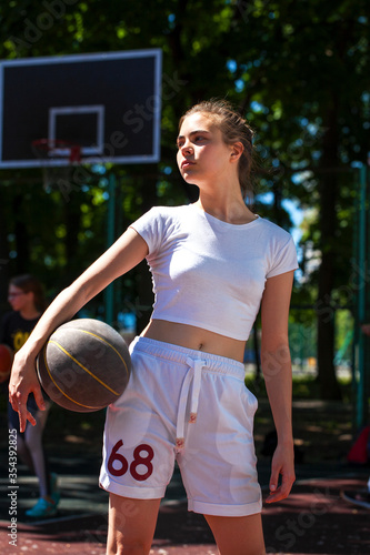 Young woman with a basketball ball posing on the playground