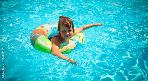 Pretty little girl in the outdoor pool at the resort. Summer holiday and happy carefree childhood concept.