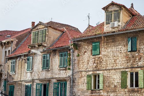 Traveling by Croatia. Ancient architecture of Split old town. Old stone house with green shutters and res tiled roof.
