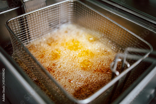 Close-up of fries in deep fryer. Restaurant meal preparation, side dish photo
