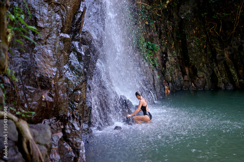 Travel and nature. Young woman swimming in tropical waterfall pool.