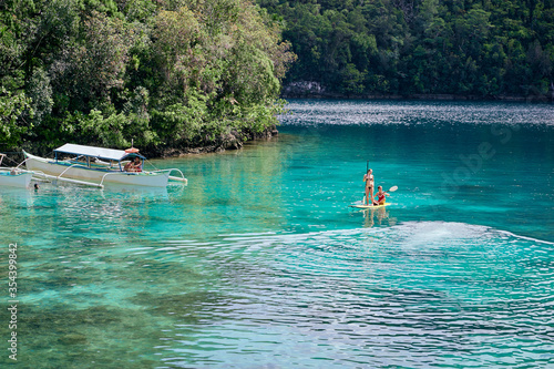 Summer holidays vacation travel. SUP Stand up paddle board. Young women sailing together on beautiful calm lagoon. photo