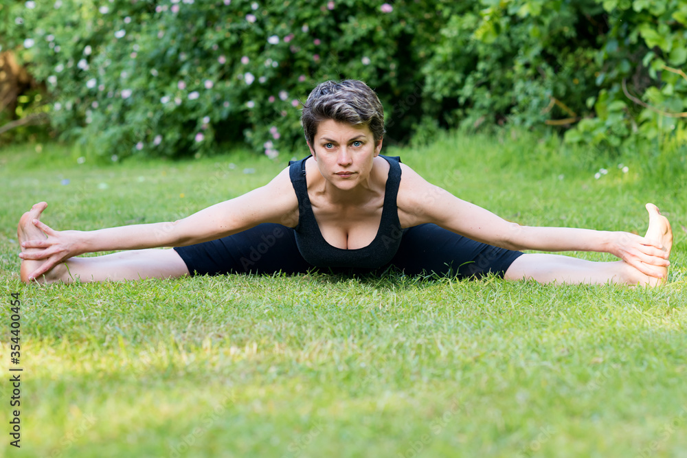 International day of yoga. Woman doing yoga outside on green grass on a sunny warm day in the park International day of yoga. Woman doing yoga outside on green grass on a sunny warm day in the park
