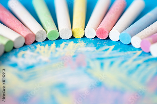 children's colored crayons arranged in a semicircle on a painted sheet of blue paper, background image