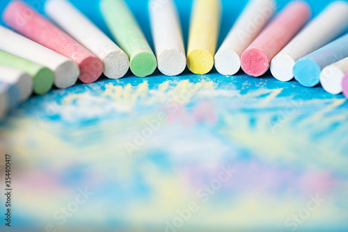 children's colored crayons arranged in a semicircle on a painted sheet of blue paper