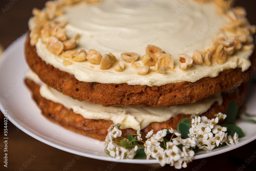 Carrot cake with hazel nuts and white flowers of meadowsweet on the wooden table Carrot cake with hazel nuts and white flowers of meadowsweet on the wooden table