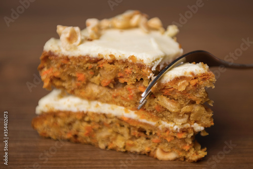 A slice of carrot cake cut by a dessert fork