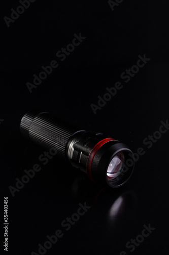 Black tactical flashlight on a black background