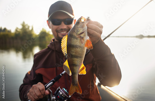 Happy angler with perch fishing trophy. 