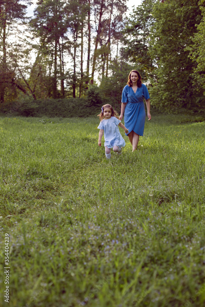 mother and daughter walk along the field with dandelions mother and daughter walk along the field with dandelions