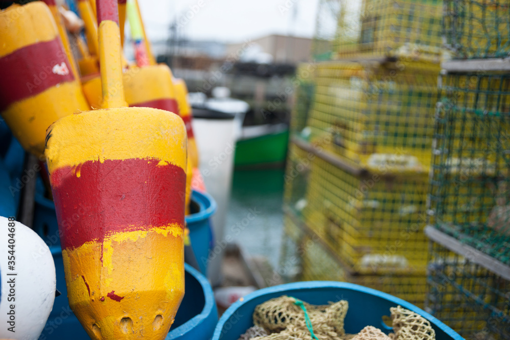 Bright colored buoys in selective focus alongside other equipment and crab traps in port1