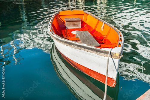 Bright orange and white painted wooden dinghy tied to pier at Boothbay photo