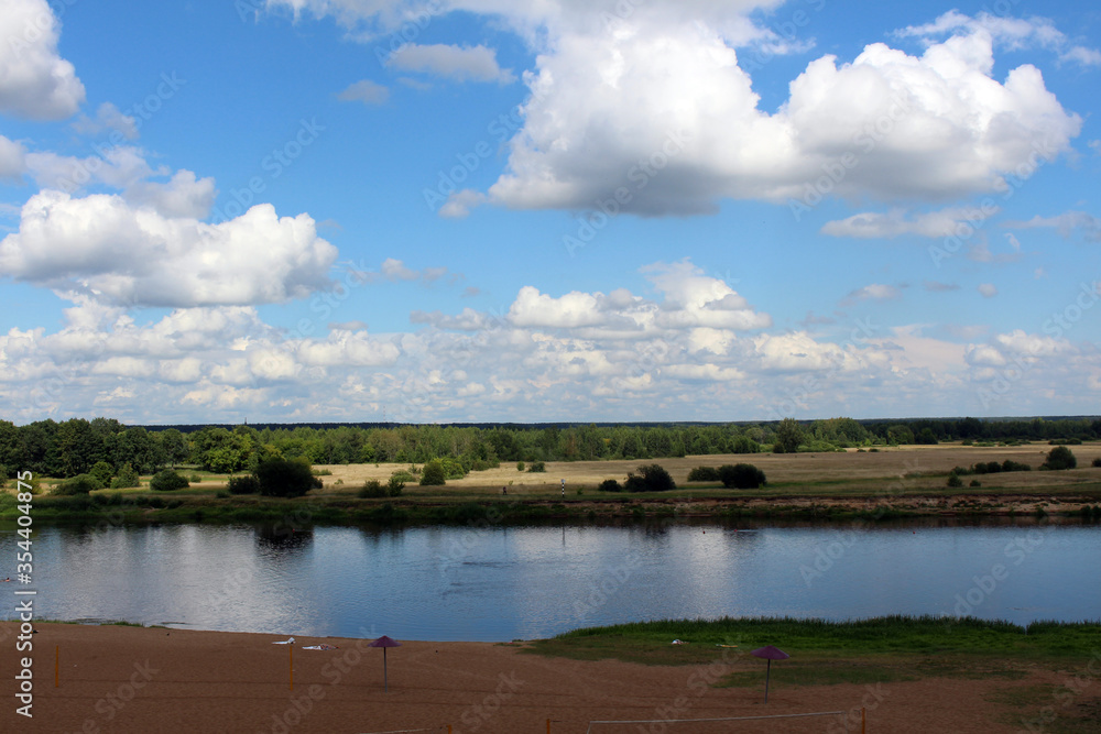 Landscape. View of the river, an empty deserted beach and a blue sky with clouds.