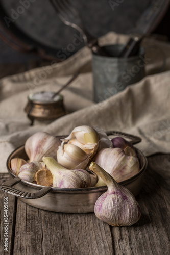 Garlic in a dish on an old wooden table. Vintage, rustic style.