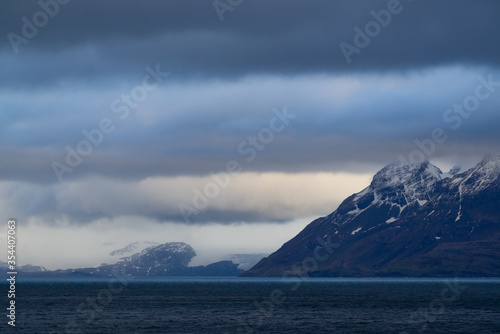 Blue reflection on the ocean with a cloudy sky and mountains © Sandra