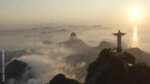 Amazing, aerial shot of a Christ the Redeemer silhouette during summer sunrise over the clouds in Rio de Janeiro Brazil