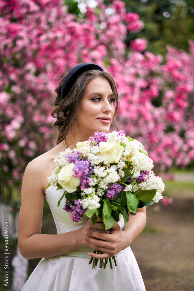 Girl with a bouquet stands at a flowering rose tree, wedding walk Girl with a bouquet stands at a flowering rose tree, wedding walk