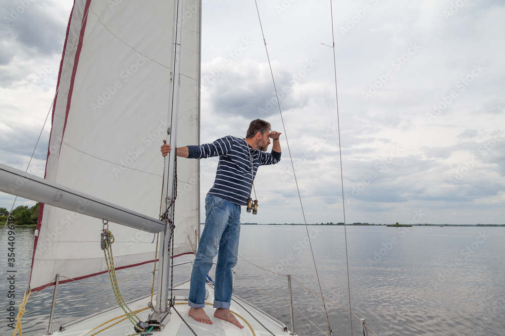 Man is sailing yacht and looking through binoculars Man is sailing yacht and looking through binoculars