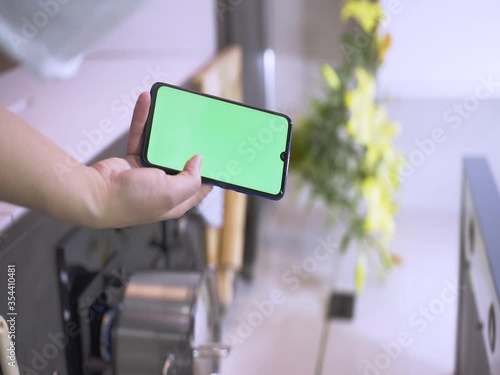 Girl using the phone Green screen in the kitchen, Hands holding the CHROME KEY business smartphone Fingers of the modern smartphone screen touching massage scrolling functions