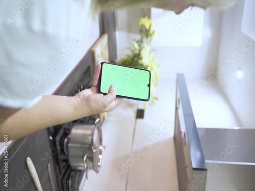 Girl using the phone Green screen in the kitchen, Hands holding the CHROME KEY business smartphone Fingers of the modern smartphone screen touching massage scrolling functions