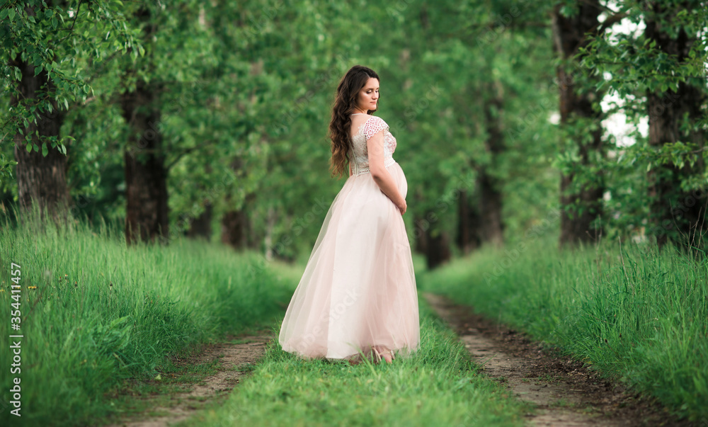Pregnant happy woman in a white dress in a forest outdoors. Beautiful nature, pregnancy concept