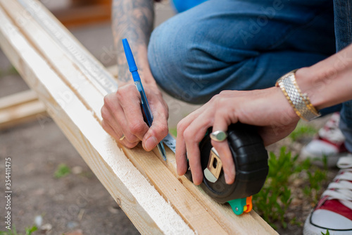 A man measures with a tape measure. Wooden product. Building made of wood. 