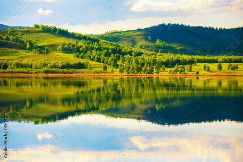 Mountains with green trees and their reflections in the lake. Beautiful summer landscape. South Ural, Russia