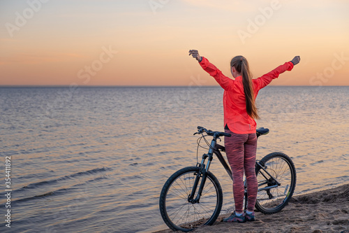 A girl stands with a bicycle