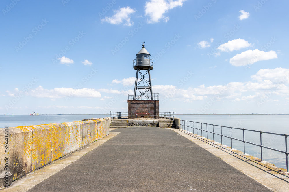  lighthouse stands at the end of a pier at the North Sea
