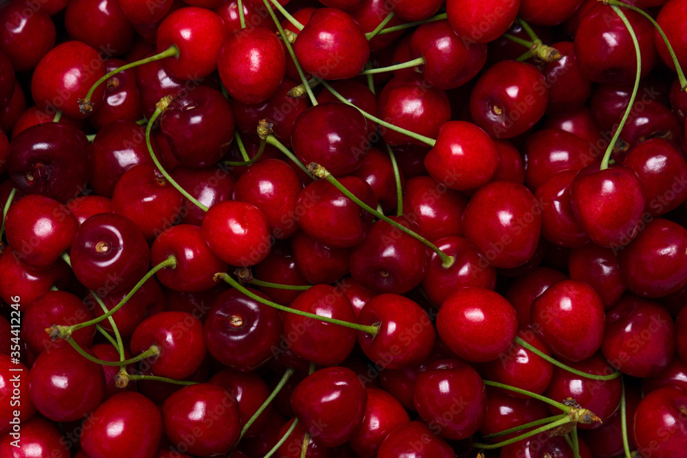 Red cherries in full screen. The texture of cherries. A lot of red cherries. Fresh ripe sweet cherries with green stems Red cherries in full screen. The texture of cherries. A lot of red cherries. Fresh ripe sweet cherries with green stems