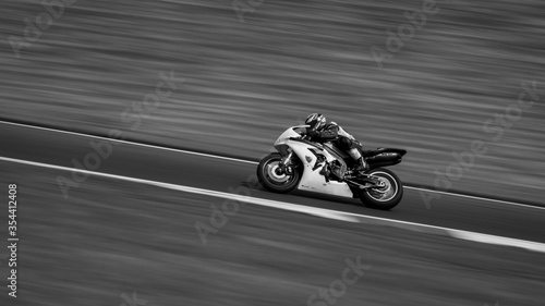 A monochrome panning shot of a racing bike cornering on a track