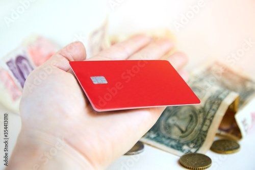 A red plastic credit card on a woman's palm. The concept of getting a loan and successful purchases with discounts, transferring paper money through an ATM