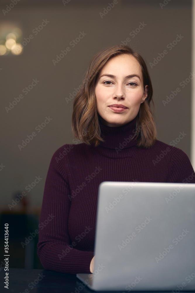 Portrait of beautiful woman in front of her laptop, looking at the camera Portrait of beautiful woman in front of her laptop, looking at the camera