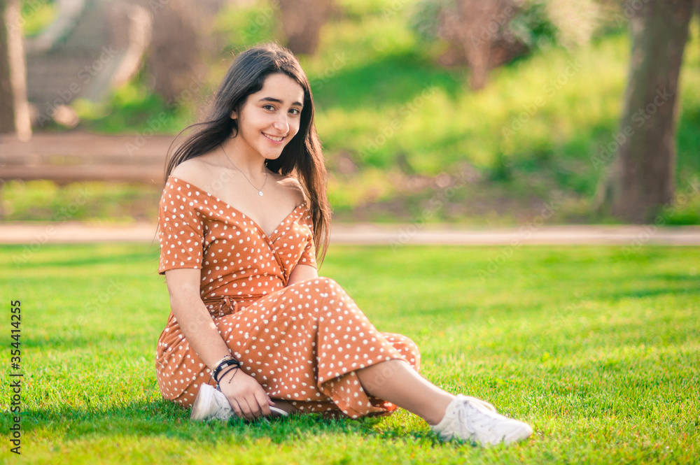 beautiful caucasian smiling girl sitting on the grass in the park looking at the camera. great copy space. beautiful caucasian smiling girl sitting on the grass in the park looking at the camera. great copy space.