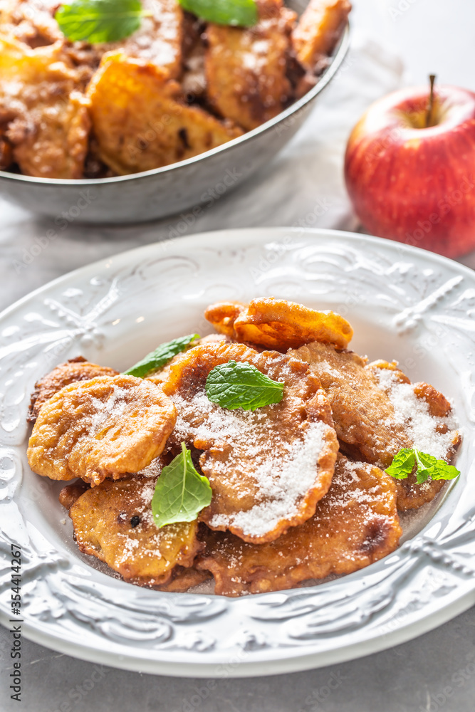 Finely fried apple pancakes sprinkled with vanilla sugar and cinnamon topped with mint leaves