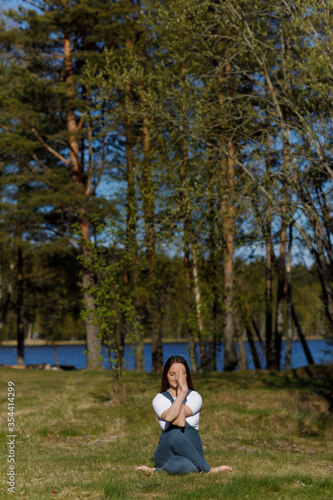 Woman practicing yoga pose in the forest nature. Playing sports on the grass in the woods Woman practicing yoga pose in the forest nature. Playing sports on the grass in the woods